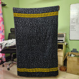 Black patterned fabric with yellow border held up in a room with green walls and office furniture.