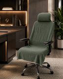A high-back office chair with a matching fabric headrest and backrest cover in a muted sage green color, styled in a modern home office setting.
